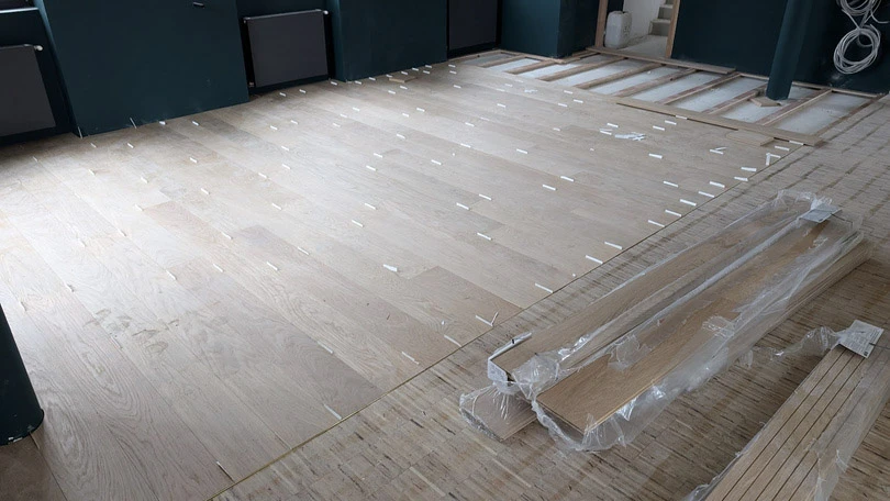 Chantier de rénovation de parquet en bois dans un espace intérieur
