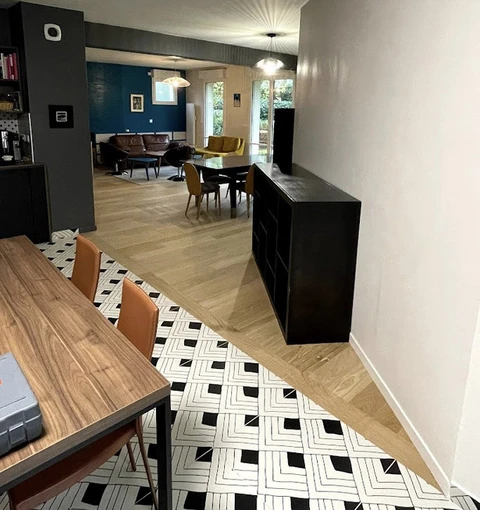 Intérieur moderne d'appartement en cours de rénovation avec parquet chêne massif et carrelage géométrique noir et blanc