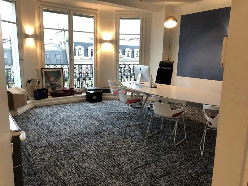 Salle de restauration moderne avec tables et chaises en bois clair disposées dans un espace lumineux aux grandes baies vitrées