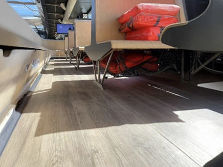 Salle de restauration moderne avec tables et chaises en bois clair disposées dans un espace lumineux aux grandes baies vitrées