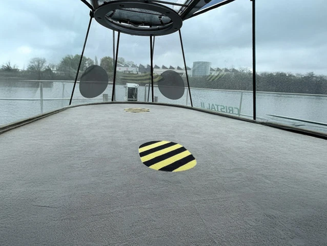 Intérieur moderne avec grande baie vitrée donnant sur rue, rangée de cylindres noirs le long des fenêtres, espace ouvert lumineux avec éclairage naturel