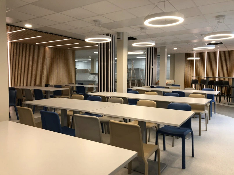 Intérieur moderne avec grande baie vitrée donnant sur rue, rangée de cylindres noirs le long des fenêtres, espace ouvert lumineux avec éclairage naturel