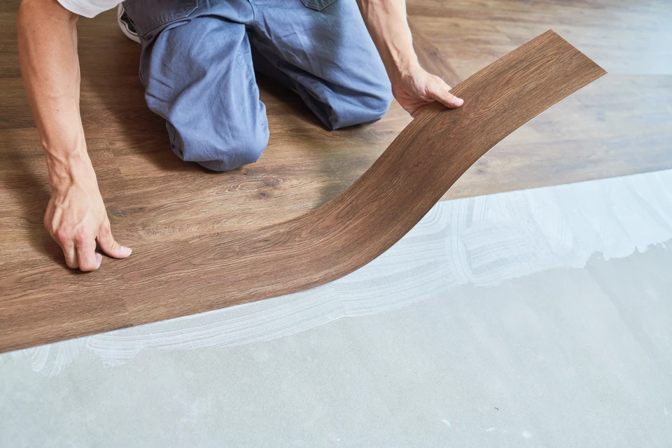 Scène d'atelier intérieur avec travailleur en gants noirs utilisant une scie égoïne sur planche de bois