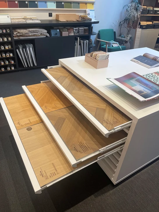 Espace de bureau moderne avec zone lounge centrale comprenant fauteuils orange pivotants, canapés gris, table basse en bois
