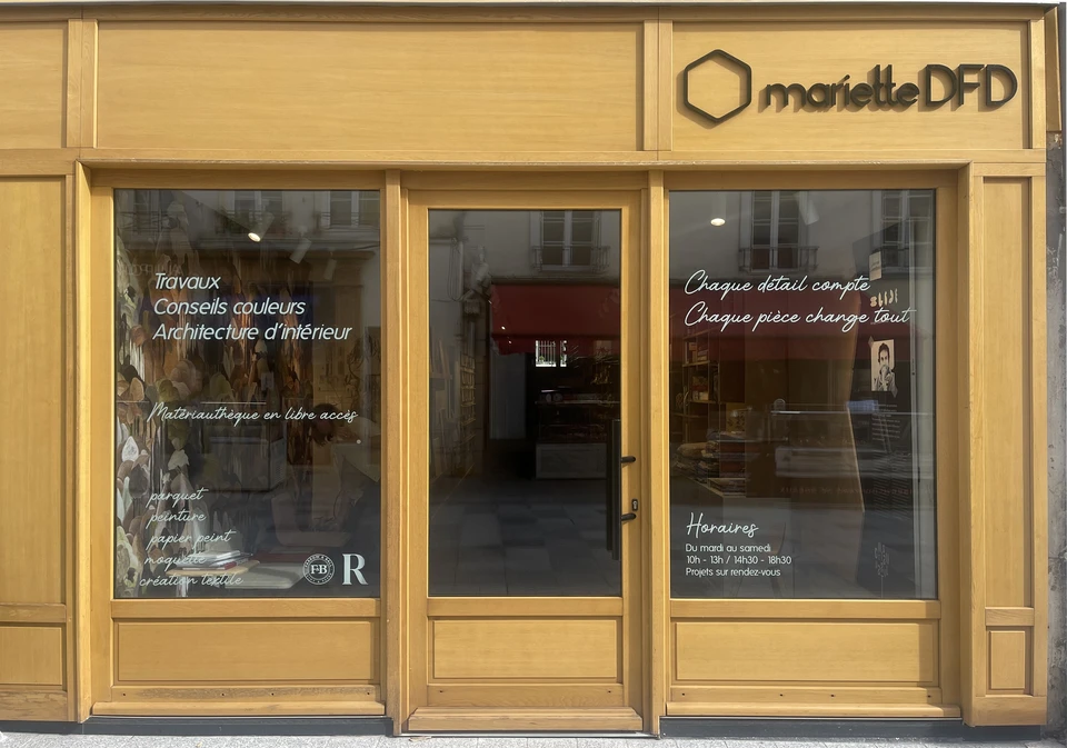 Femme souriante pr&eacute;sentant &eacute;chantillon de parquet dans showroom d'am&eacute;nagement int&eacute;rieur