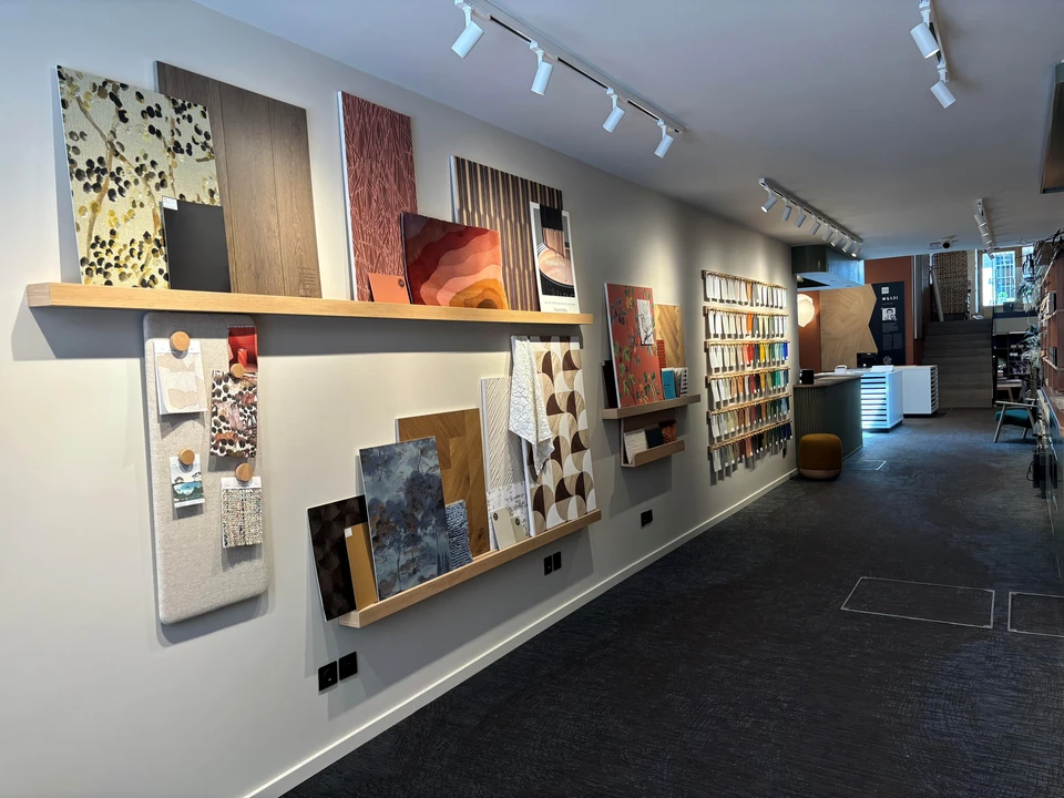 Femme souriante pr&eacute;sentant &eacute;chantillon de parquet dans showroom d'am&eacute;nagement int&eacute;rieur