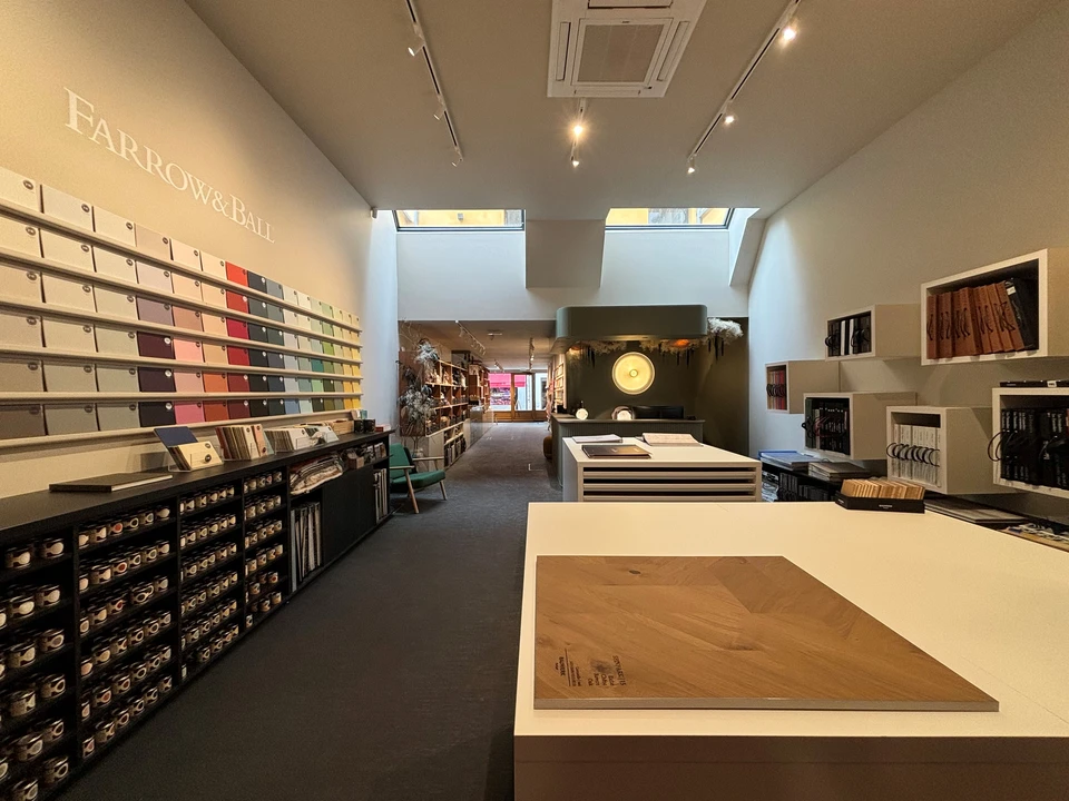 Femme souriante pr&eacute;sentant &eacute;chantillon de parquet dans showroom d'am&eacute;nagement int&eacute;rieur