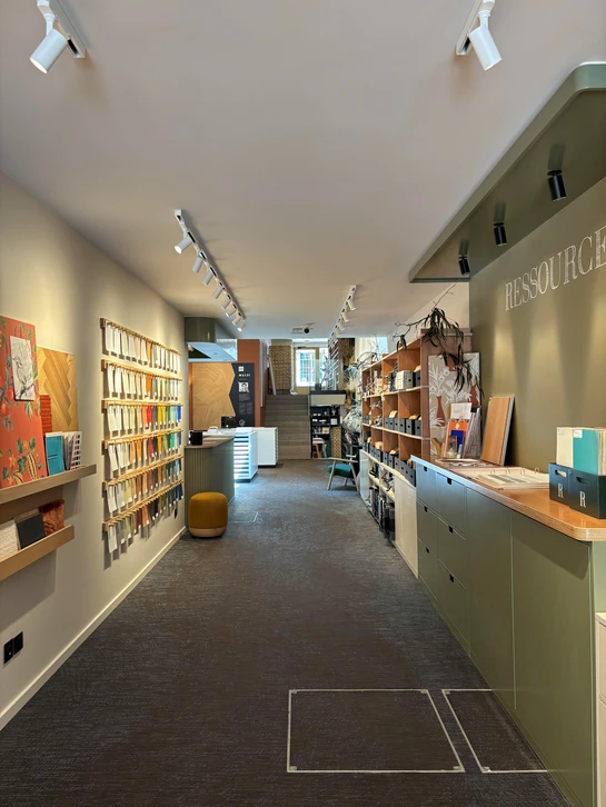 Femme souriante pr&eacute;sentant &eacute;chantillon de parquet dans showroom d'am&eacute;nagement int&eacute;rieur