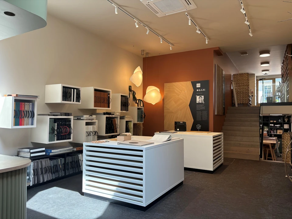 Femme souriante pr&eacute;sentant &eacute;chantillon de parquet dans showroom d'am&eacute;nagement int&eacute;rieur